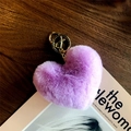 Close-up of a fluffy purple heart keychain with a gold metal ring on a magazine - Violet