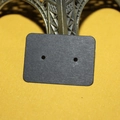 Detail of a black kraft paper earring display card leaning against a metal Eiffel Tower model - 500 Pieces/Pack / Black