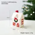 White ceramic Christmas house with a red roof, green wreath, and warm glowing LED lights - Red Fairytale House E