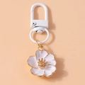 Détail d'un porte-clés fleur en émail blanc aux bords dorés et crochet à ressort blanc - Blanc