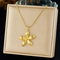 Detailopname van een vergulde bloemenhanger ketting op een beige sieradendoosje - Bloem Stijl (N3560)