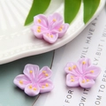 Macro shot of three purple resin cherry blossom charms with yellow stamens for DIY crafts - Purple