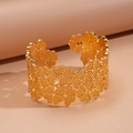 Dettaglio macro del bracciale rigido dorato con motivi floreali traforati di lusso - Oro