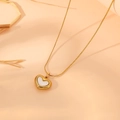Detalle macro de un collar de corazón dorado con incrustación de nácar blanco en tonos cálidos - Collar de Corazón Único Dorado (B412)