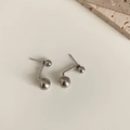 Macro di orecchini a lobo con sfere d'argento su sfondo crema con texture naturale - Bottone a Doppia Sfera / Argento