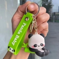 Close-up of cute panda plush keychain with green bamboo and Panda Baby wrist strap - Bamboo Panda - Lying on Bamboo