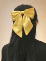 Large ginger yellow satin bow hair clip accessory worn on a woman's dark hair - Spring Clips / Ginger Yellow