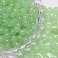 Macro shot of 8mm green translucent glass beads with gold wire patterns for DIY jewelry - Jasper Green Brushed