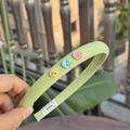 Light green fabric headband with colorful button accents and Alline brand label - Fresh Green Narrow Headband with Multi-Color Buttons