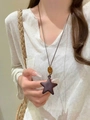 Detail of a brown star-shaped resin pendant with an amber bead on a waxed cord necklace - Black Star Style