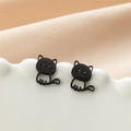 Dettaglio macro di orecchini a gatto nero opaco su un piatto di porcellana bianca - Nero