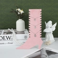 Pink velvet boot-shaped jewelry stand displaying three elegant necklaces on a green backdrop - Pink