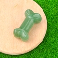 Aventurine green crystal bone carving displayed on a round wooden base and green turf - Green Aventurine