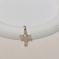 Dettaglio del ciondolo a croce placcato oro con pietre di zircone su un piatto bianco - Zircone Bianco/Trasparente