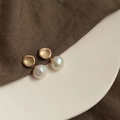 Detail of baroque pearl drop earrings featuring matte gold geometric studs on linen texture - Style 1