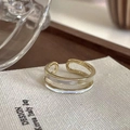 Close-up of a double-layered gold ring with white enamel on a beige textile mat - Adjustable Open / Spliced Shell Style