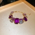 Détail d'un bracelet fleuri doré avec cristaux violets sur un plateau texturé - 14# Bracelet-Doré Violet Géométrique