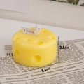 Cheese shaped scented candle in bright yellow with realistic hole texture and white label - Round Cheese