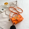 Vibrant orange crossbody handbag with gold baroque buckle on a beige blazer setting - Orange