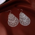 Detailed view of silver hollow leaf floral earrings on dark premium silk fabric - Hook Style / Silver