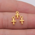 Three tiny golden cross charms with rings for DIY jewelry shown on a person's fingertip - Bright Gold