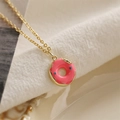 Vue macro d'un collier doré avec pendentif donut en émail rose et pépites bleues - Donut Rose