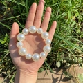 Elegant French style hair scrunchie with large white pearls held in a person's palm - Mixed Size Pearl Style