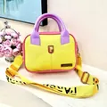 Macro shot of pebbled leather texture with yellow and purple color block design on a handbag - Yellow