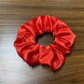 Close-up of a glossy red satin LED scrunchie placed on a dark wooden background - Red [three-level Headlights]