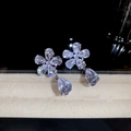 Nahaufnahme der Blumenohrringe aus Silber mit Zirkonia-Tropfen auf dunkler Reflexionsfläche - Silberohrring-Posten - Silber