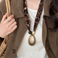 Detail of leopard print fabric necklace with amber resin pendant on a female model - Green Oval Pendant / Coffee