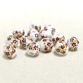 Dettaglio macro di perle in ceramica bianca da 10 mm con motivi floreali marroni e foglie arancioni - Piccolo Fiore di Prugno Caffè