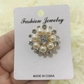 Detalle del elegante broche de flor dorada con perlas blancas y brillantes piedras de strass - Estambre de perla circular