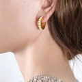 Elegantes pendientes en forma de C dorados con perlas incrustadas en una modelo - Dorado