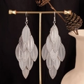 Macro detail of silver layered leaf earrings hanging on a minimalist display stand - Long Textured Leaf / Silver