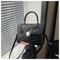 Detalle de bolso negro textura cocodrilo con hebilla giratoria redonda y asa fija - Negro