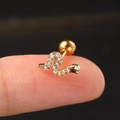 Macro view of a gold snake stud earring with clear zircon inlay held on a finger - Gold Snake Zircon Stud
