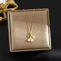 Vista dettagliata di una collana a foglia di ginkgo dorata con zirconi su un portagioie - Oro-Ginkgo