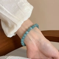 Primo piano di un elegante bracciale di agata verde chiaro al polso con pizzo bianco - Blu Perle Tonde (65#)