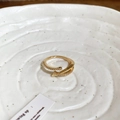 Primer plano de un anillo cruzado dorado con circonitas en una bandeja de cerámica blanca - Estilo Abierto Cruzado con Circonita / 2# Anillo-Dorado