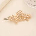 Vista detallada de una pinza para el pelo de mariposa dorada con perlas sobre fondo beige - Estilo Perla / Dorado