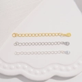 Macro detail of S925 sterling silver heart and drop extension chains in gold and silver - Waterdrop Tag / Gold
