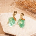 Detalle de pendientes de hoja con discos de concha verde y ganchos dorados sobre piedra - Verde