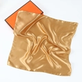 Detail of a golden silk scarf with soft texture beside an elegant orange gift box - Gold