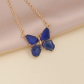 Close-up of golden butterfly pendant with blue zircon stones on pink silk fabric - 4# Royal Blue Necklace