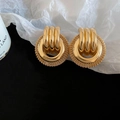 Macro view of gold vintage earrings with intricate mesh texture and hollow twisted rings - Gold