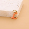 Minimalist golden letter L pendant with orange enamel finish on a beige stone base - Enamel Letter-L