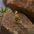 Macro shot of a square green gemstone pendant in gold setting on a natural rock surface - Natural Peridot Square Pendant Gold