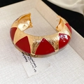 Detailopname van een Franse vintage manchetarmband met rood emaille en metaaltextuur - Brede Versie / Rood/Goud