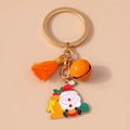 Detailed shot of Christmas keychain with Santa on a sleigh, orange tassel and golden bell - Orange Santa Claus